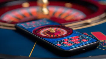 A man celebrating a winning moment on his laptop while gaming symbols float around him, capturing the excitement of 777DBET games.